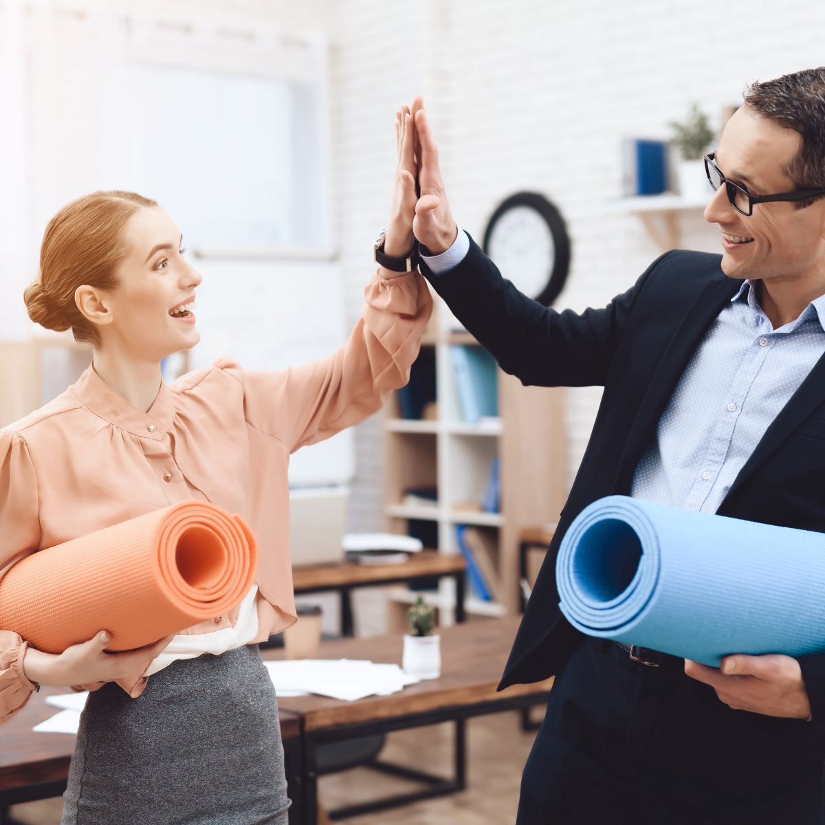 Coworkers high five leading up to a personalized corporate fitness activity as a part of a Houston corporate wellness program.