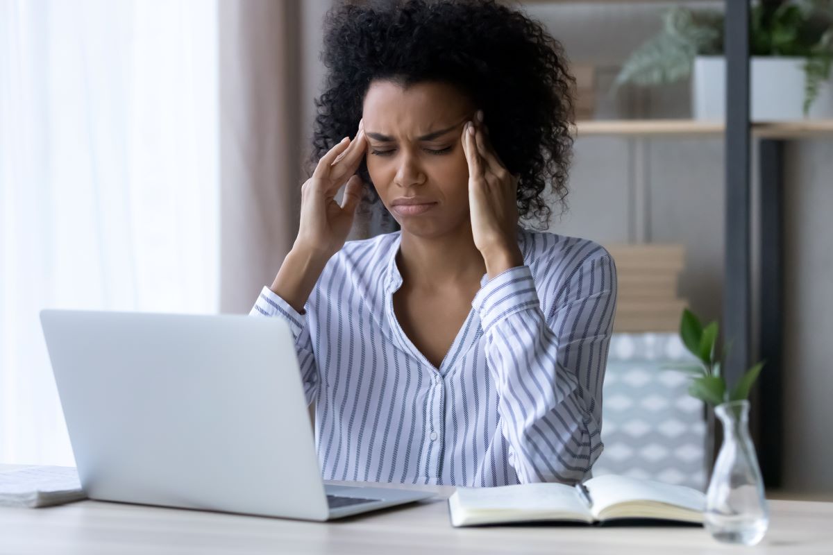 Stressed worker sits at desk showing a need for a Houston corporate wellness program
